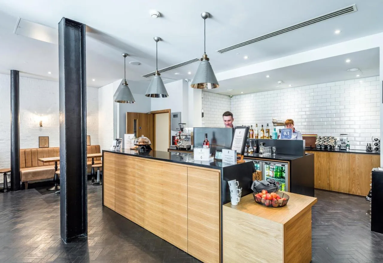 a restaurant with a counter with a man behind the counter at The Z Hotel Glasgow in Glasgow
